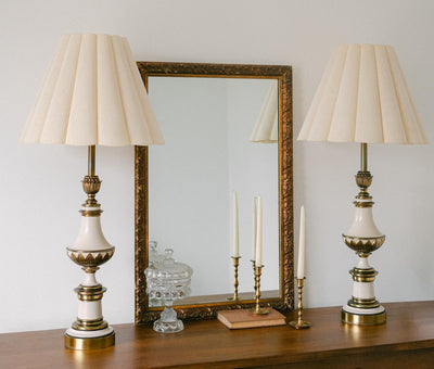 A balanced pair of tall vintage Stiffel porcelain and brass table lamps, styled here in a quiet, symmetrical entryway arrangement