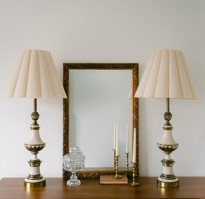 A balanced pair of tall vintage Stiffel porcelain and brass table lamps, styled here in a quiet, symmetrical entryway arrangement