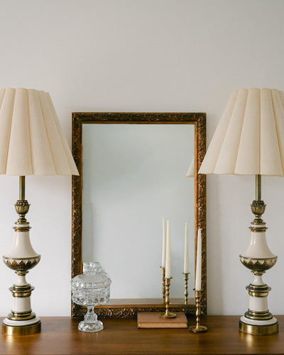 A balanced pair of tall vintage Stiffel porcelain and brass table lamps, styled here in a quiet, symmetrical entryway arrangement