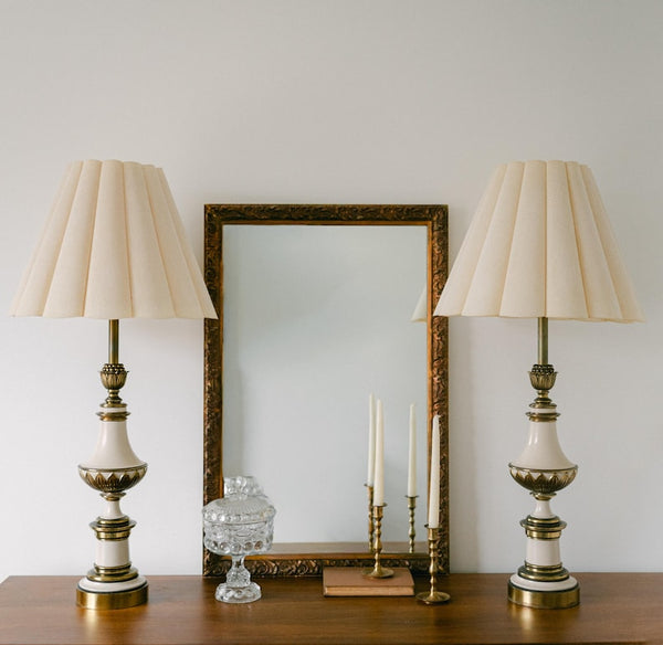 A balanced pair of tall vintage Stiffel porcelain and brass table lamps, styled here in a quiet, symmetrical entryway arrangement